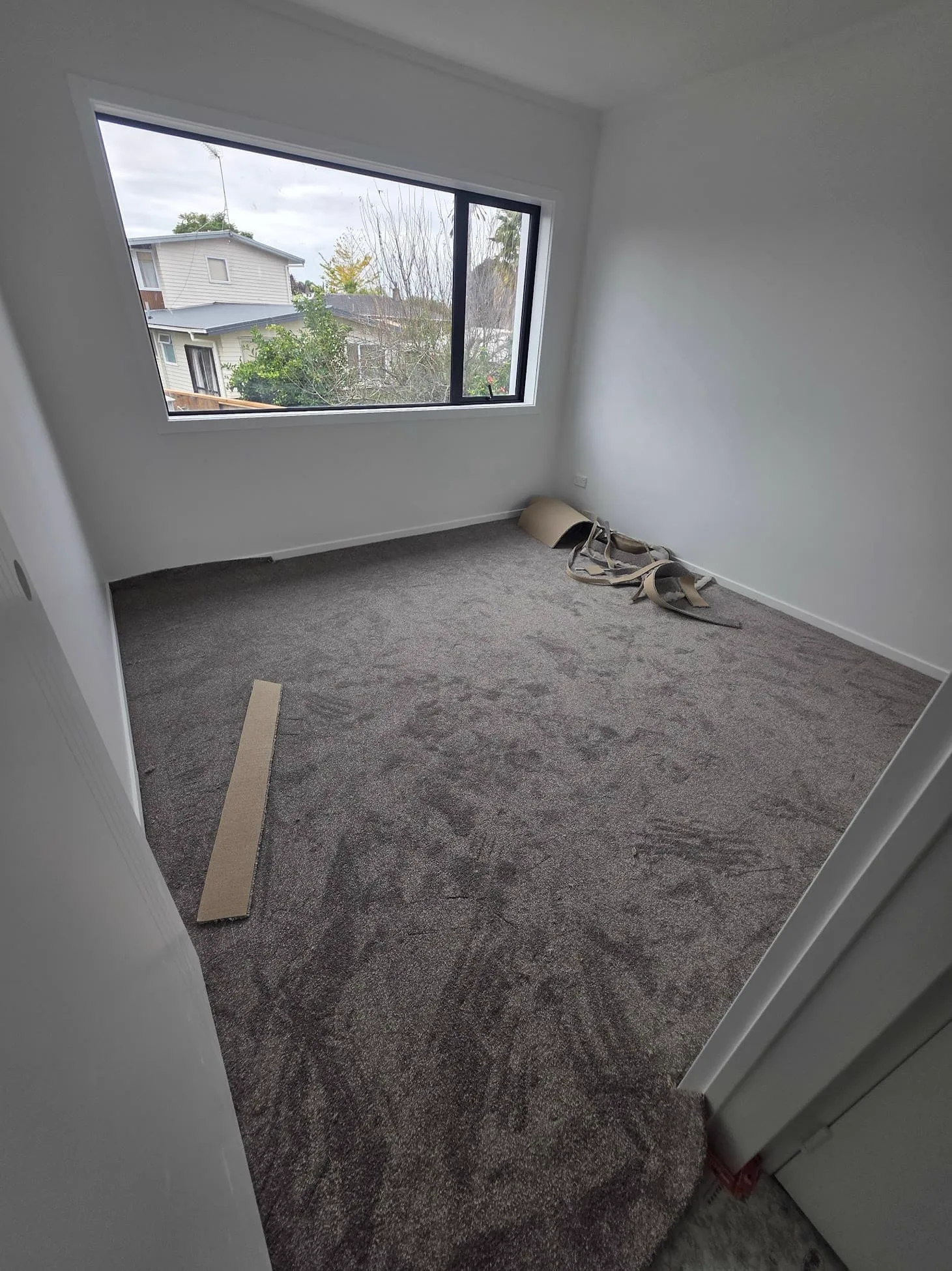 The same bedroom earlier in the job, with offcuts and gripper strip on the floor before the trims go on