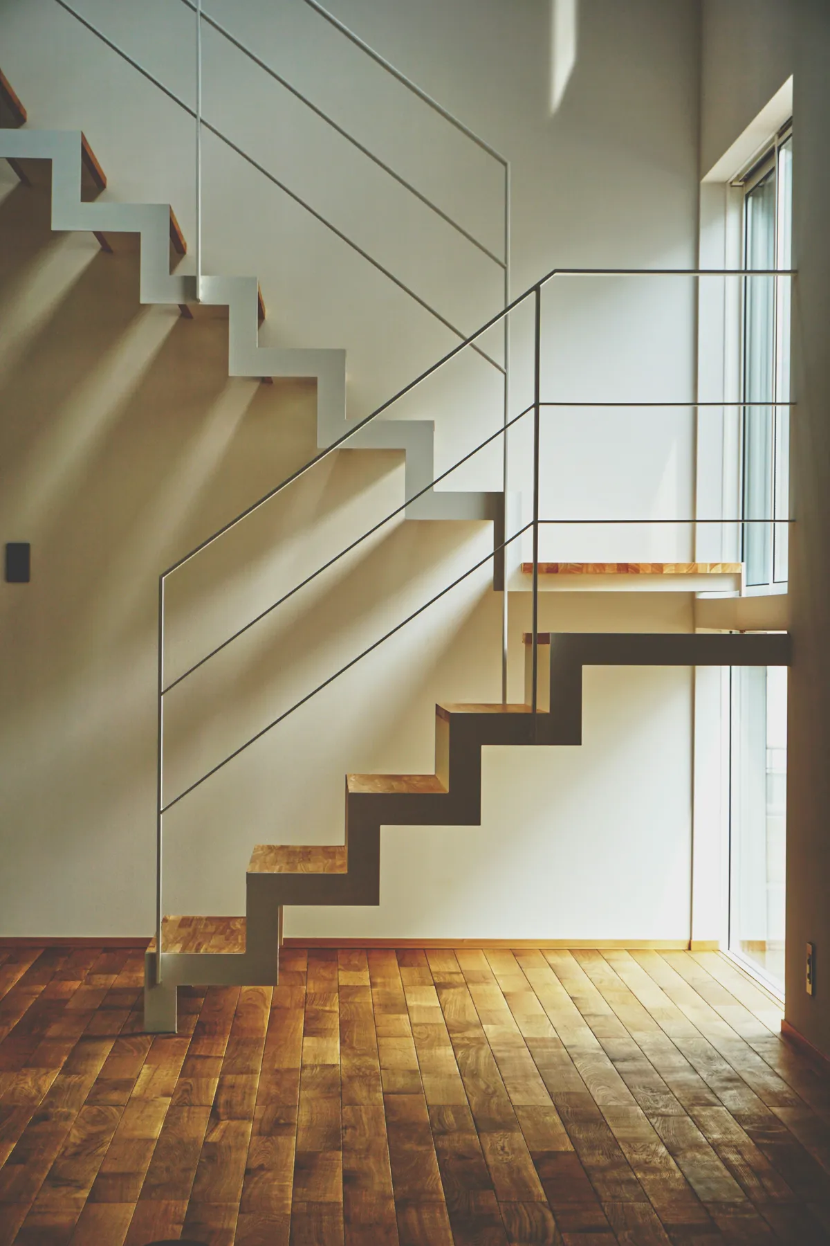 Modern floating staircase with a white steel frame over light oak plank flooring